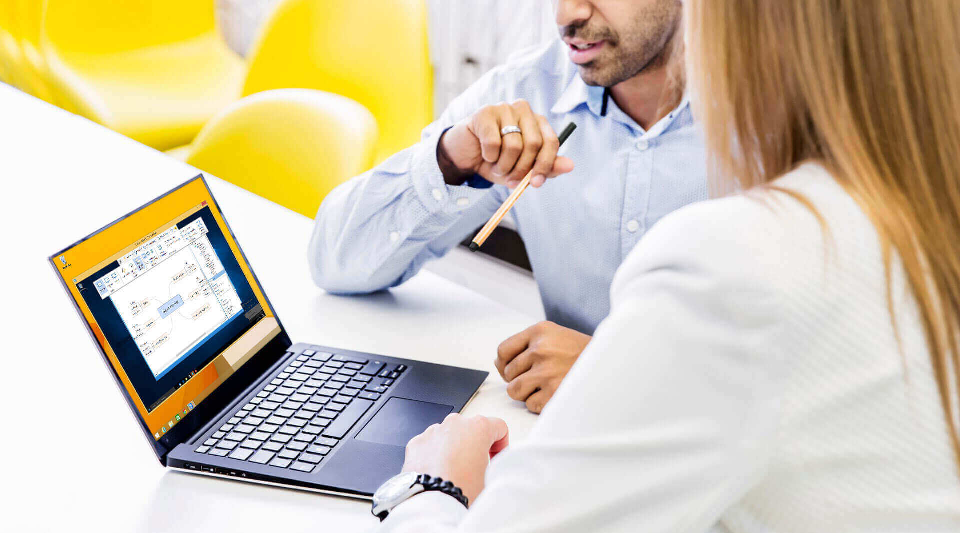 Мужчина и женщина используют функцию демонстрации экрана и показывают на ноутбук во время совещания