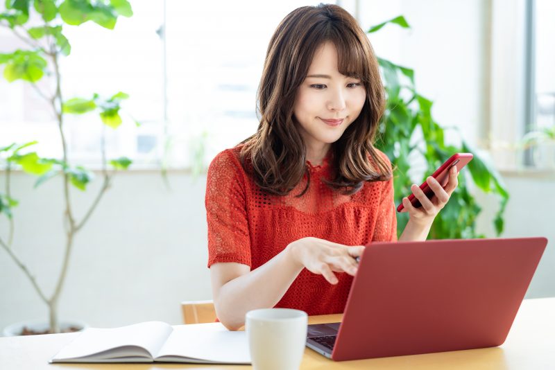 asian woman working remotely using TeamViewer Mac Remote Desktop while holding iphone